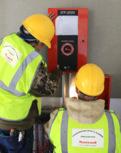 Countryside Alarms employees installing an IFP 2000 fire panel 