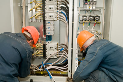 two electrical contractors wiring an industrial panel